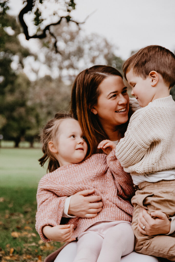 A mother embraces her two children during a photoshoot at Princes Park