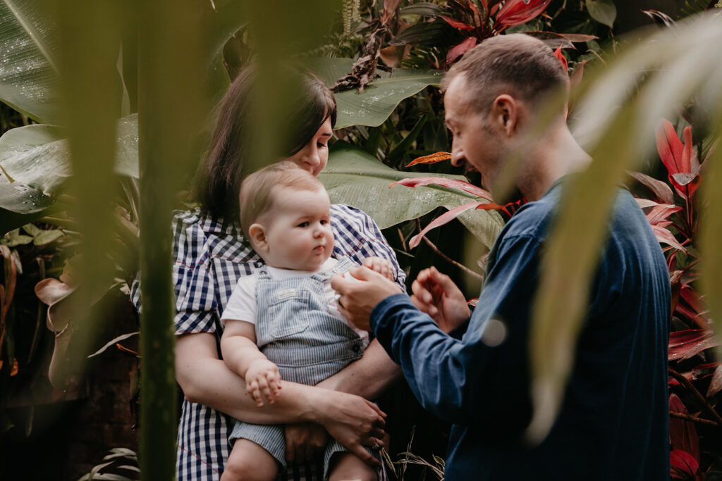 A family of three engage with each other inside the tropical glasshouse at the Royal Botanic Gardens in Melbourne. 